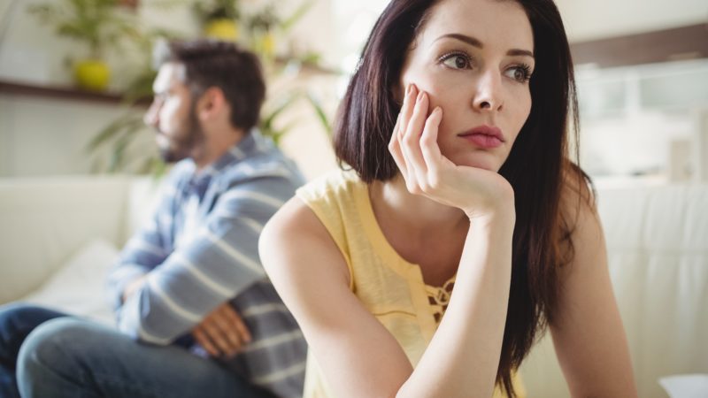 Upset couple ignoring each other on sofa