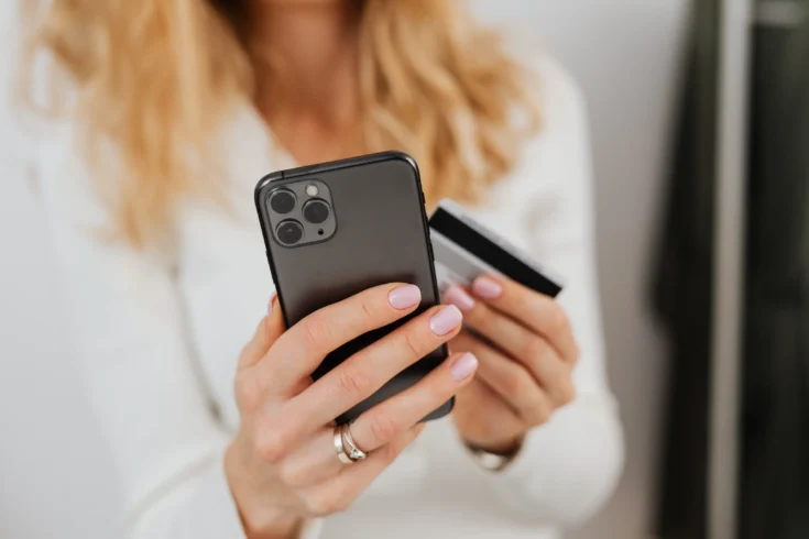 Close up of a person holding a credit card and a smartphone